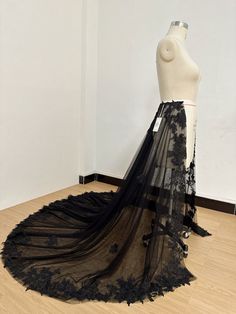 a mannequin wearing a black dress on display in a room with white walls