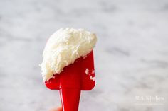 a person holding a red and white object with some food on it's tip