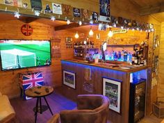 a bar with two chairs and a television on the wall in front of it that is lit up