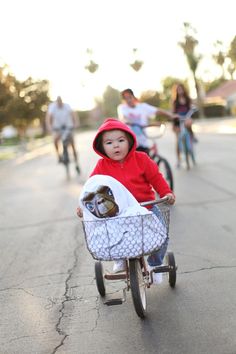 a little boy riding on the back of a bike with a baby in it's stroller