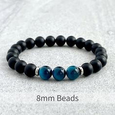 Men's beaded bracelet features: ~ 6mm, 8mm or 10mm matte onyx beads ~ 6mm, 8mm or 10mm aqua blue tiger eye beads ~ 4mm, 6mm or 8mm stainless steel spacers ~ Stretchy cord; simply slide bracelet on and off wrist ~ Comes packaged in a re-usable microfiber pouch To ensure the perfect fit, please use the bracelet sizing instructions found in the photo gallery. Blue Beaded Bracelets For Men, Masculine Bracelets, Mens Jewelry Diy, Blue Tiger Eye Bracelet, Bracelet Man, Blue Tiger Eye, Slide Bracelet, Blue Beaded Bracelets, Blue Tiger