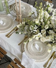 a table set with plates, silverware and flowers