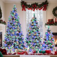 three decorated christmas trees in front of a fireplace