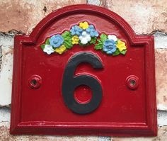 a red mailbox with flowers on the number six