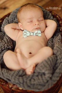 a baby sleeping in a basket with a bow tie