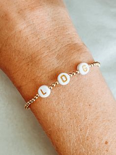 "the daintiest little gold beaded bracelet is the perfect piece to show off your love for your family! include up to 7 initials of your kids, family members, or favorite people to carry around with you wherever you go! each one is custom made to order in your size with your choice of gold or black initial beads!  MADE WITH GOLD FILL BEADS - \"gold fill\" beads are high quality and they don't tarnish or fade like \"gold plated\" beads. the difference is a long-lasting premium piece of jewelry tha Initials Bracelet, Bracelet For Mom, Family Bracelets, Gold Beaded Bracelet, Paw Print Charm, Bracelet Initial, Personalized Mother's Day Gifts, Monogram Jewelry, Gold Bead Bracelets