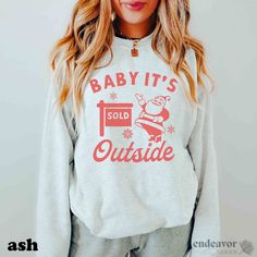 a woman wearing a sweatshirt that says baby it's outside and santa clause on the front