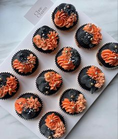 cupcakes decorated with orange and black frosting on top of a white board