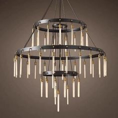 a chandelier made out of metal and glass tubes with gold trimmings