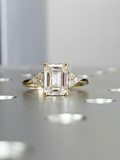 an emerald cut diamond ring with three diamonds on the side