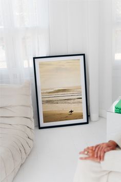 a woman laying on the floor in front of a framed photograph with a surfboard