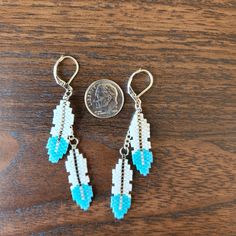 the earrings are made out of seed beads and turquoise glass bead, with a penny in the background