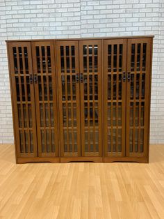 a wooden cabinet with glass doors on the front and back sides, against a white brick wall