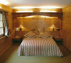 a bed in a room with wood paneling and two lamps on either side of the bed