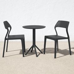 two chairs and a table are shown in front of a white wall, one is black