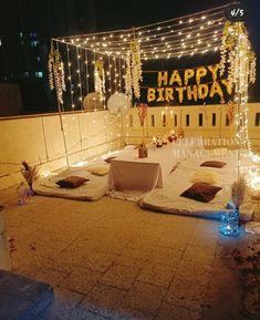 an outdoor birthday party setup with lights and decorations on the side of a building at night