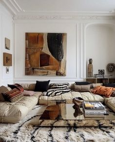 a living room filled with lots of furniture next to a painting on the wall above a coffee table