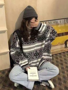 a woman sitting on the floor with her hand covering her face while holding a book