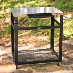 a small metal table sitting on top of a stone floor in front of some grass