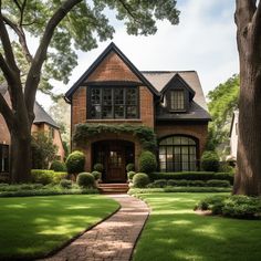 a brick house surrounded by lush green grass and trees in front of it is a pathway leading to the front door