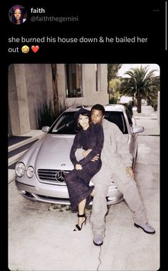 a man and woman sitting on the hood of a car in front of a building