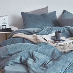 a blue comforter with a cup and saucer on it next to a table