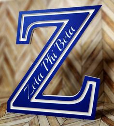 a blue and white z logo on a wooden floor with chevron tiles in the background