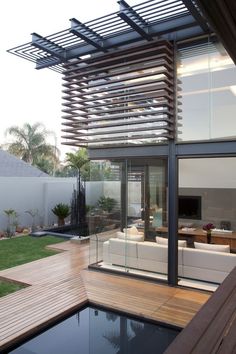 an outdoor living area with wooden decking and glass walls