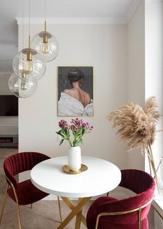 a white table with two chairs and a vase filled with flowers on top of it