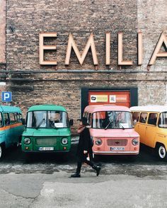 three different colored vans parked next to each other in front of an old brick building