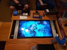 two people sitting at a table with electronics on it