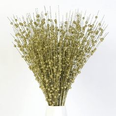 a white vase filled with lots of gold colored flowers