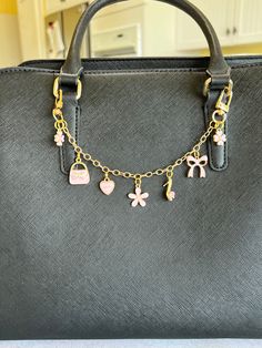 a black purse with gold chains and charms hanging from it's handles on a table