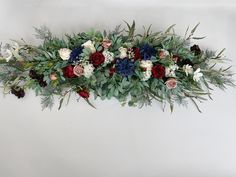 an arrangement of flowers and greenery on a white background