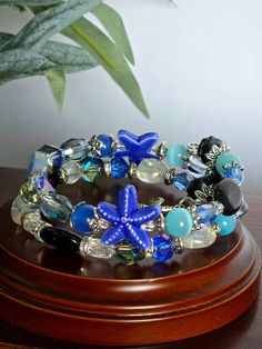 This bracelet is uniquely handmade. It includes semi-precious stones blue sandstone, Quartz, crystal, glass, and a starfish charm. This is an easy-to-wear bracelet with no clasp just wrap around your wrist. This bracelet is made to fit most wrists because there is no clasp making it adjustable to each individual wrist. Add a touch of elegance and style to your outfits with our double wire bracelet. Made with high-quality materials, this versatile accessory is perfect for any occasion. Upgrade your accessory game and enhance your look with this stunning bracelet today! wonderful gift for yourself or others. Adjustable Blue Starfish Jewelry, Ocean-inspired Blue Starfish Bracelets, Blue Natural Stones Bracelets For Beach, Blue Natural Stone Bracelets For Beach, Blue Natural Stone Beach Bracelets, Blue Starfish-shaped Beaded Bracelets As Gift, Blue Beaded Bracelet With Starfish Charm As Gift, Blue Beaded Bracelets With Starfish Charm As Gift, Handmade Blue Wrap Bracelet For Beach