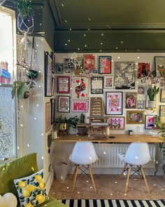 a living room filled with lots of pictures and plants on the wall next to a window