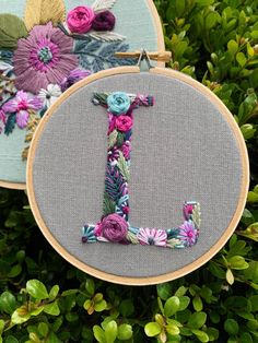 two embroidery hoops with flowers and the letter j on them, one has a flowered initial