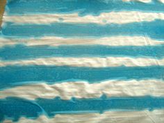 a piece of cloth with blue and white paint on it sitting on top of a wooden table