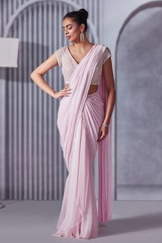 Pastel pink pre-draped saree with crystals, cutdana and sequins embroidered borders. Comes with a blouse.
Components: 2
Pattern: Embroidered
Type Of Work: Crystals, Sequins, Cutdana
Neckline: V Neck
Sleeve Type: Short
Fabric: Saree: Georgette, Blouse: Soft net, Lining: Shantoon
Color: Pink
Other Details: 
Heavily embroidered blouse
Attached lining
Length:
Saree: 44 inches
Blouse: 14 inches
Closure:
Saree: Side zip
Blouse: Back hooks
Occasion: Destination Wedding - Aza Fashions Side Zip Blouse, Short Sleeve Blouse Design, Work Crystals, Saree Georgette, Draped Saree, Drape Saree, Saree Blouse Designs Latest, Georgette Blouse, Embroidered Border