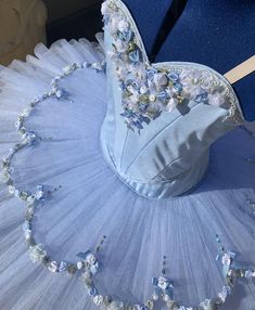 a blue dress with white flowers and pearls on the skirt is being displayed in front of a mannequin