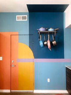 a kitchen with blue walls, orange doors and pots and pans hanging on the wall