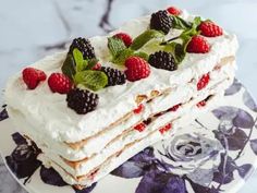 a layered cake with raspberries and mint leaves on top is sitting on a plate