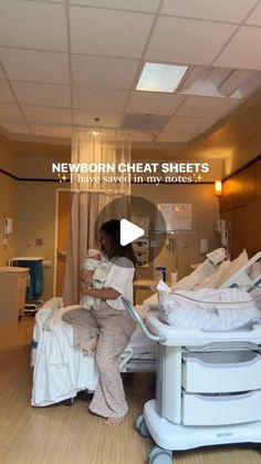 a woman holding a baby in a hospital room with lots of cots on the floor