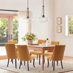 a dining room table with yellow chairs and a chandelier hanging from the ceiling