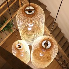 three lights hanging from the ceiling in a room with wooden steps and stairs behind them