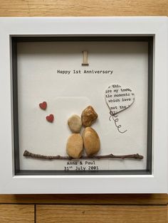 two rocks are sitting on a branch in a shadow box with the words happy 1st anniversary