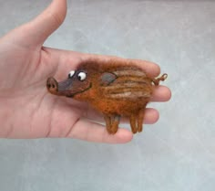 a hand holding a tiny stuffed animal with eyes