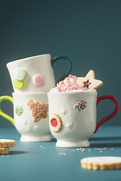 two coffee mugs filled with different types of food and candy on top of each other