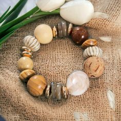 a close up of a bracelet on a burlap surface with flowers in the background