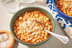 a bowl of macaroni and cheese soup with a spoon next to it on a table